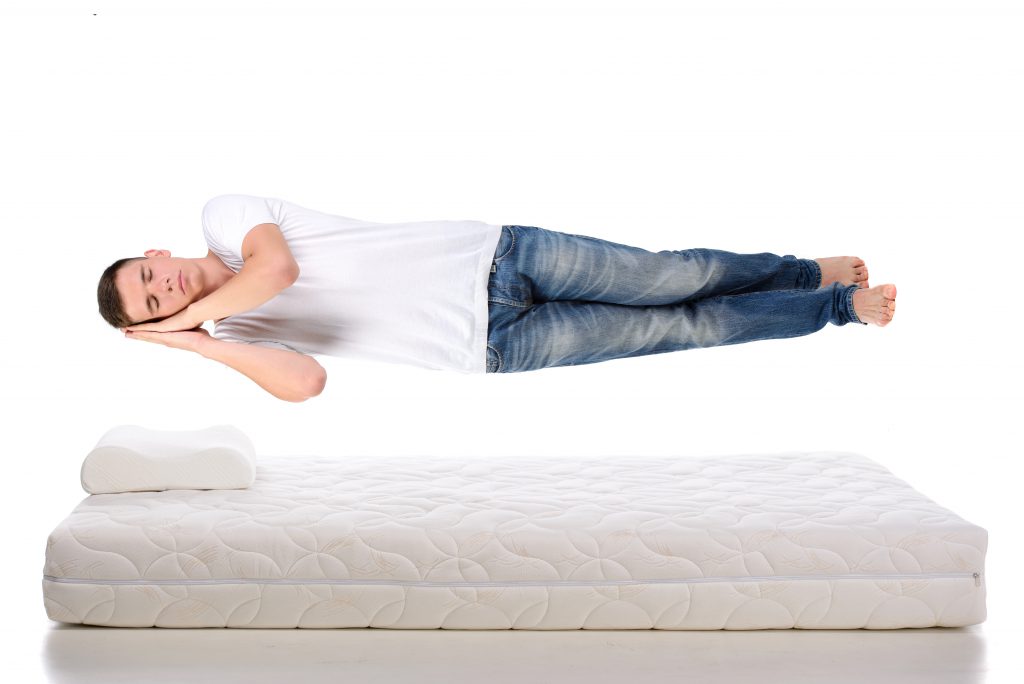 Young man sleeping on a mattress flying during sleep.